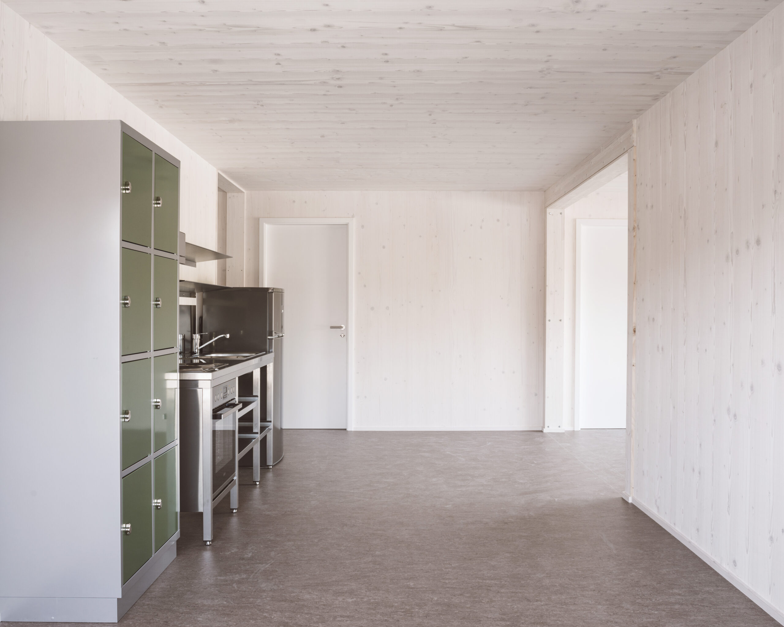 Innenraum mit Küche und Schliessfächern, und einem Durchgang zum nächsten Raum